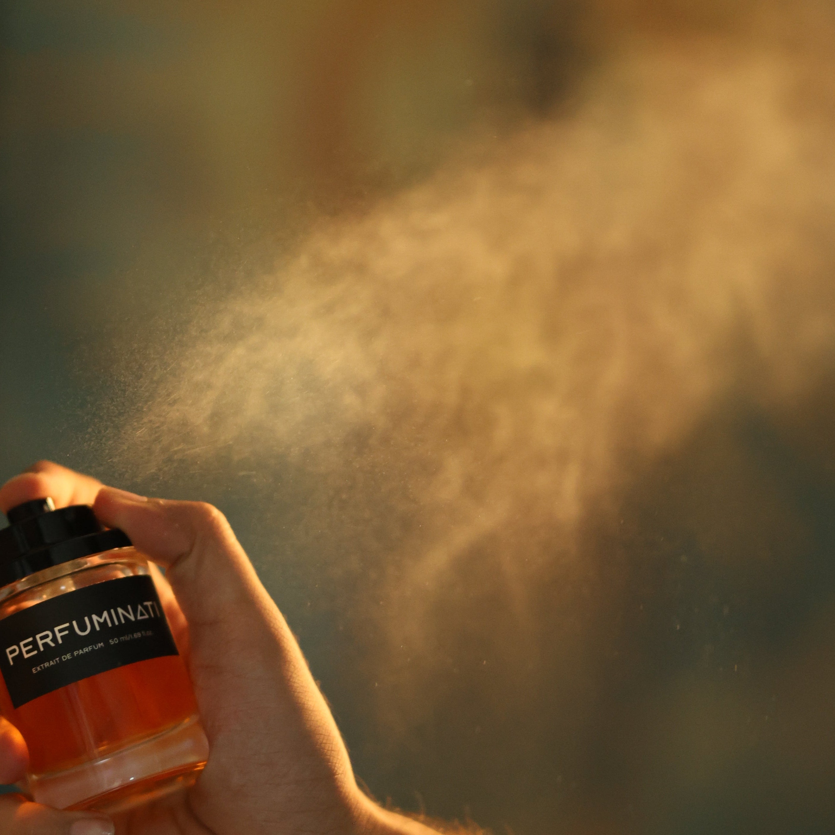 Hand holding a perfume bottle with spray mist against a blurred background